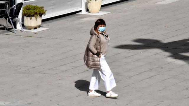 Una mujer pasea con mascarilla por La Marina