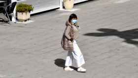 Una mujer pasea con mascarilla por el parque de La Marina