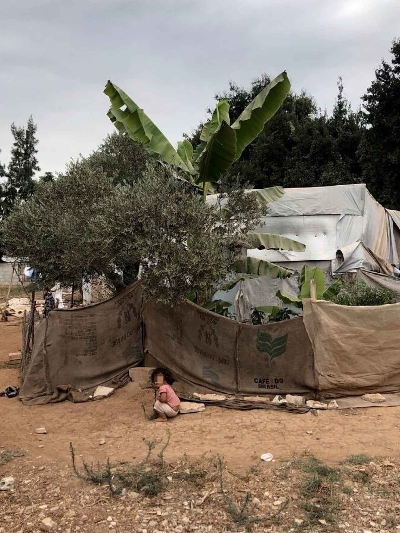 Una niña juega en un campamento informal cerca de la ONG.