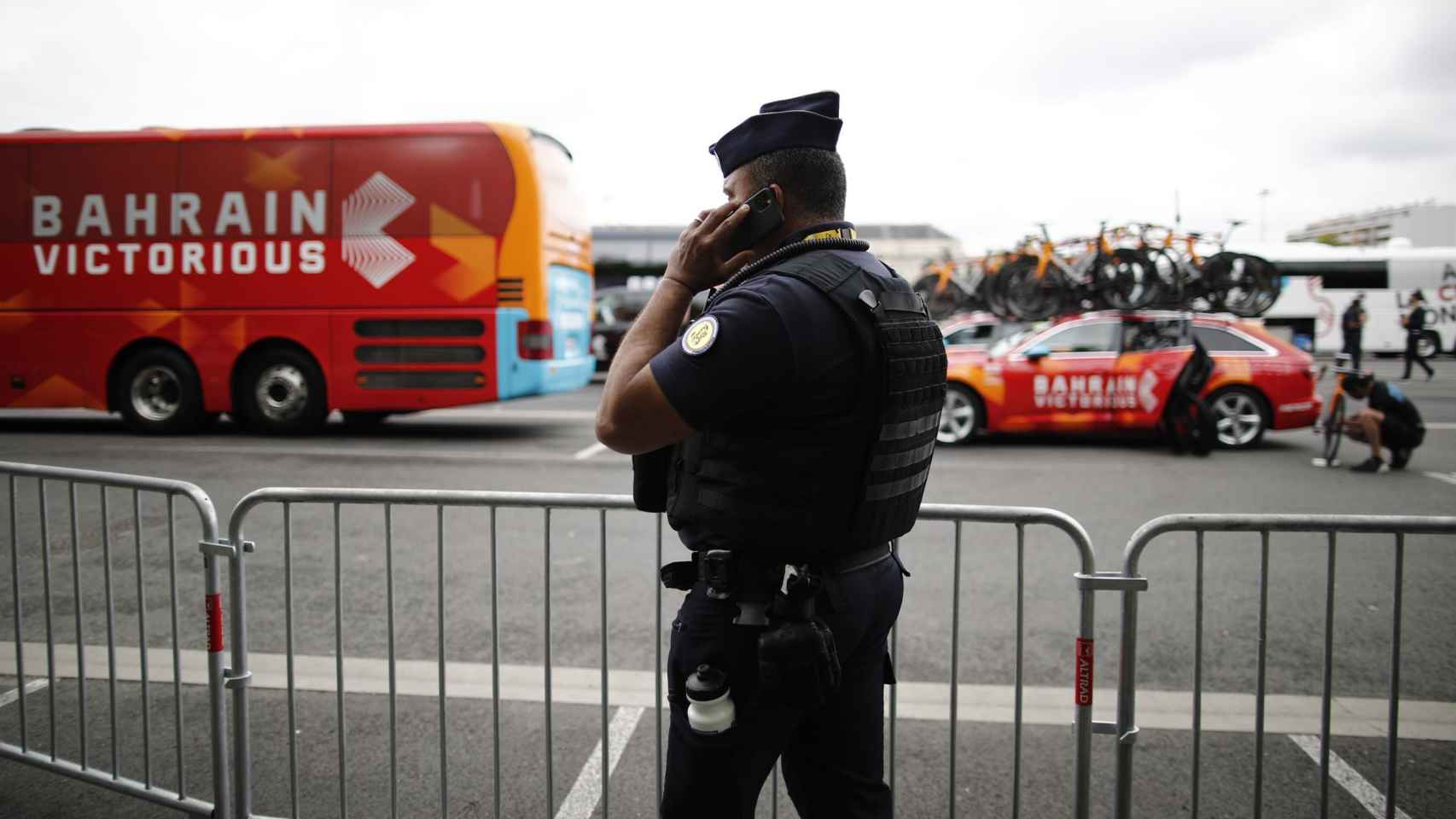 Un gendarme delante del autobús y uno de los coches del Bahrain Victorious durante el Tour de Francia 2021