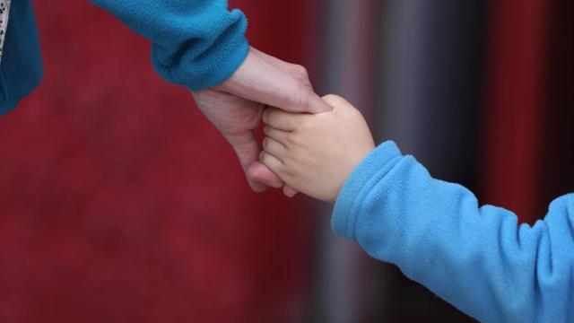 Un niño camina de la mano de un adulto