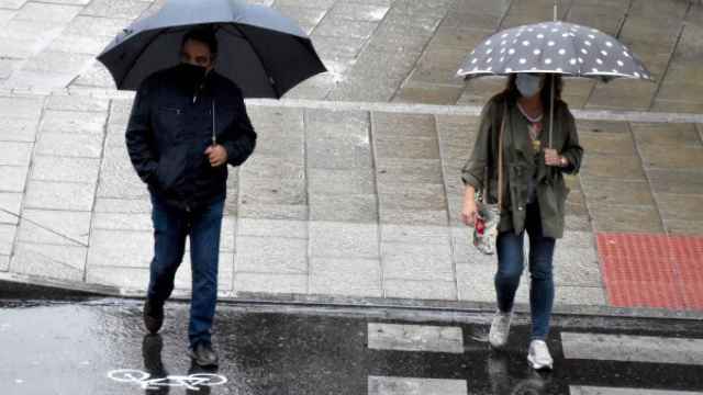 Dos personas se protegen de la lluvia con sus paraguas.