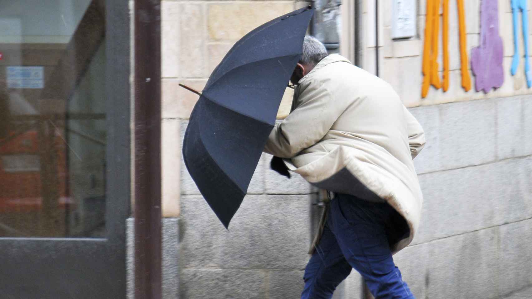 Un hombre se guarece del viento con su paraguas - ICAL