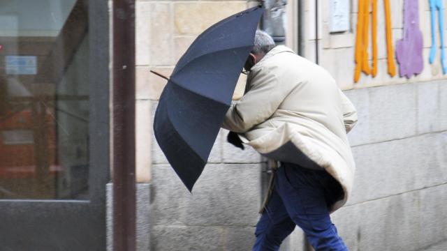 Un hombre se guarece del viento con su paraguas - ICAL