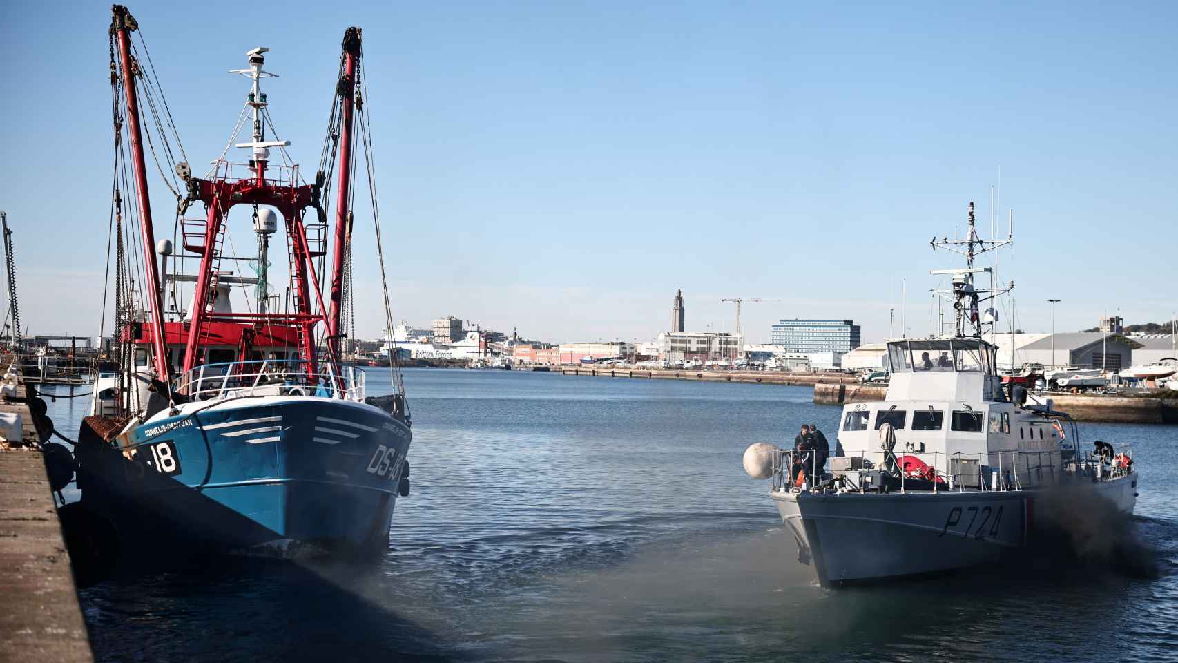 Un barco la Gendarmería francesa deja el puerto de Le Havre mientras un arrastrero británico sigue atracado.