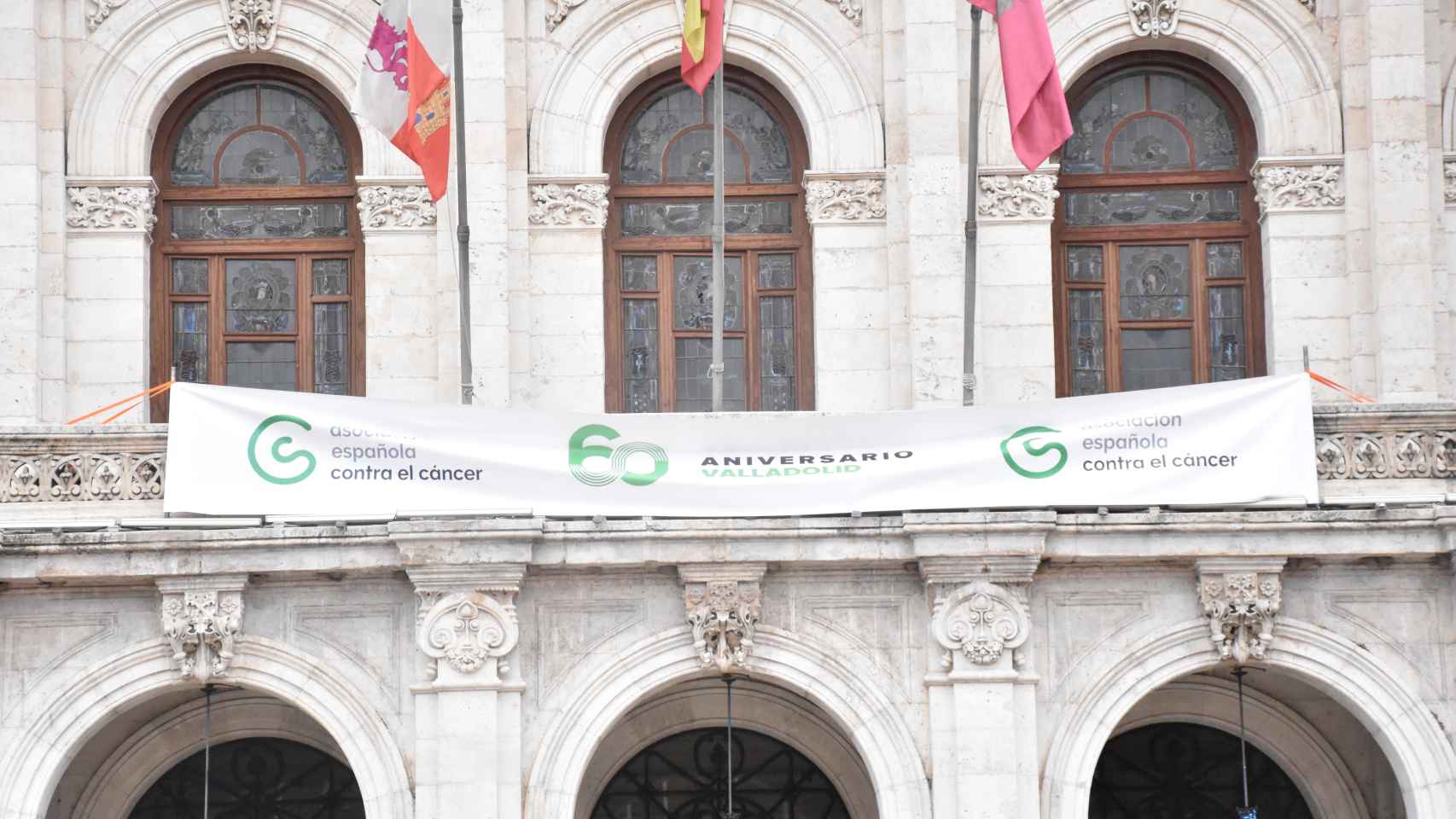 Una pancarta en el balcón del Ayuntamiento conmemora el 60 aniversario de la AECC en Valladolid
