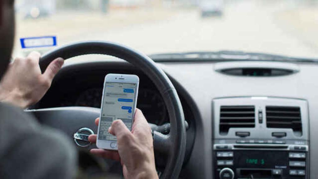 Un conductor utilizando su teléfono en el interior del coche.