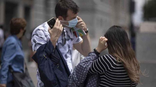 Dos personas quitándose la mascarilla.