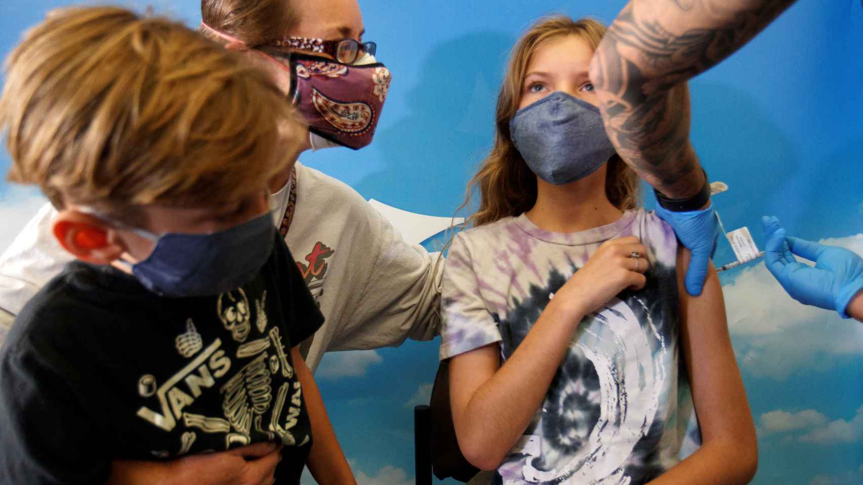 Una niña, acompañada de su madre y de su hermano, recibe la vacuna de Pfizer en San Diego.