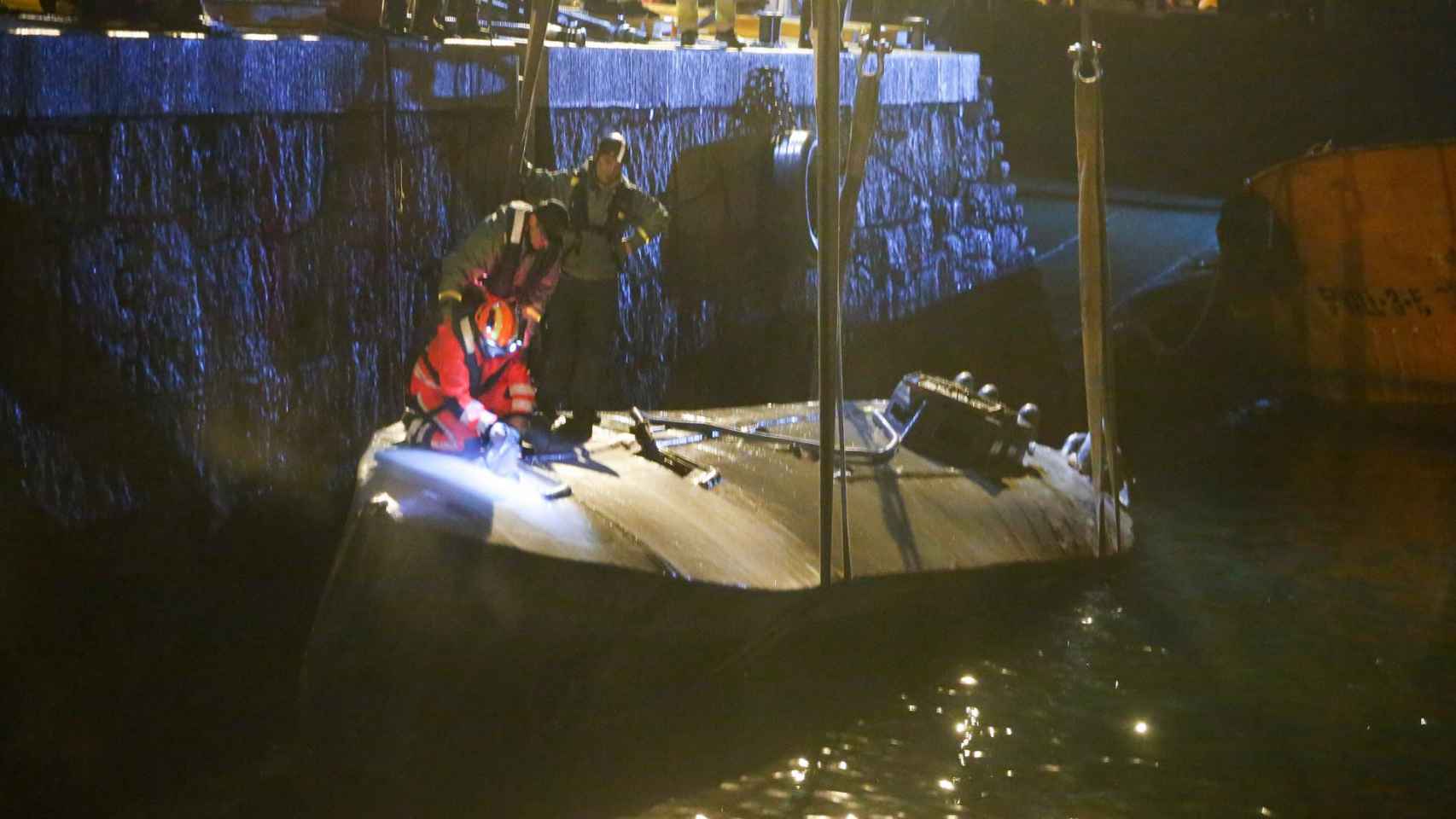 Agentes de la Policía y de la Guardia Civil haciendo labores de izado del buque en la ría de Aldán.