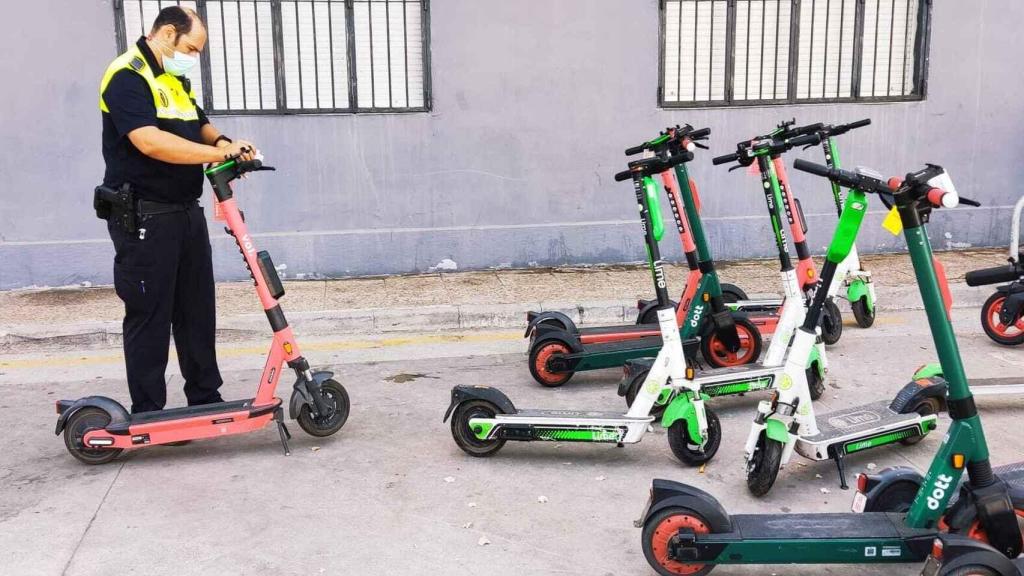 Imagen de archivo de un operario municipal multando a varios patinetes mal aparcados en Málaga.