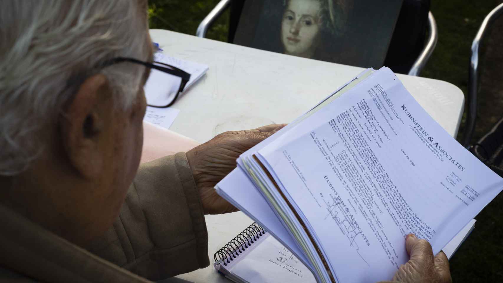Santos, en su casa de Oleiros, revisando los documentos recopilados tras 20 años de búsqueda. Al fondo, la copia de su Goya robado.