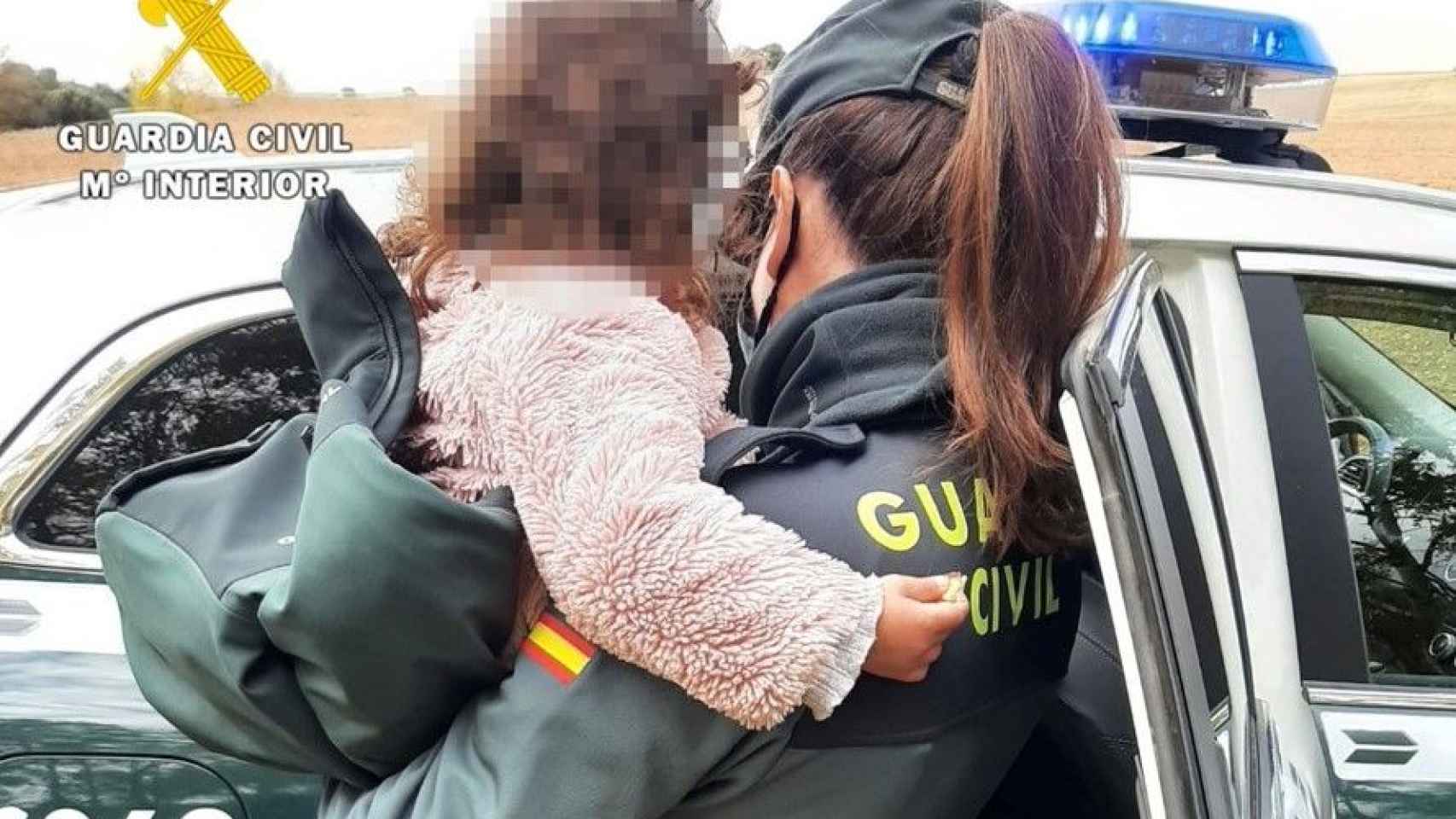 Una agente de la Guardia Civil sostiene a la niña momentos antes de entregársela a sus padres