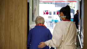 Una enfermera acompaña a una mujer mayor.