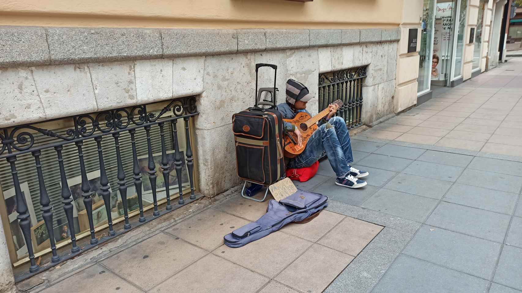Un hombre pide limosna mientras toca la guitarra en el paseo de Zorrilla de Valladolid.