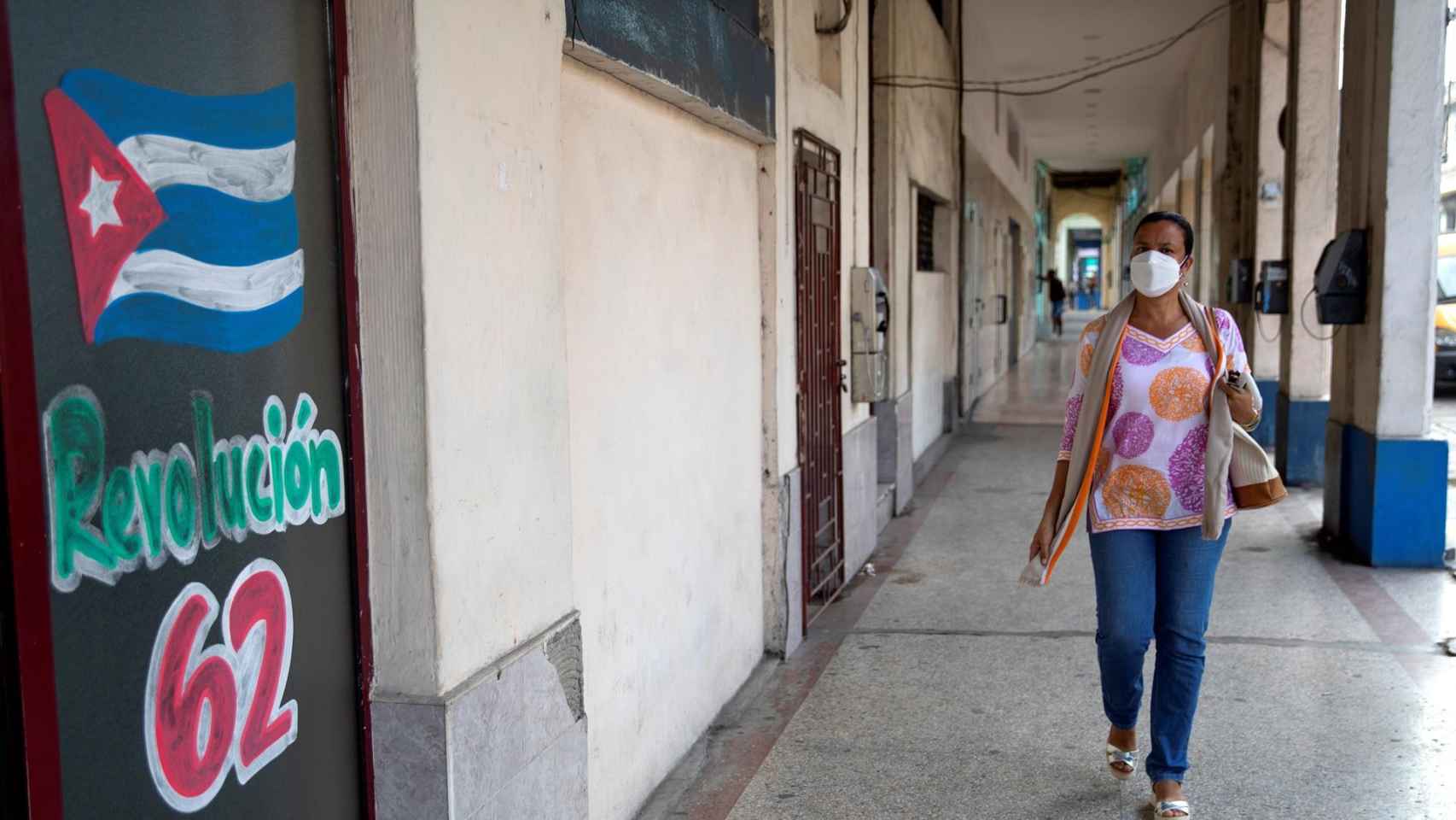 Una mujer camina hoy junto a un dibujo en apoyo a la Revolución Cubana, en La Habana.