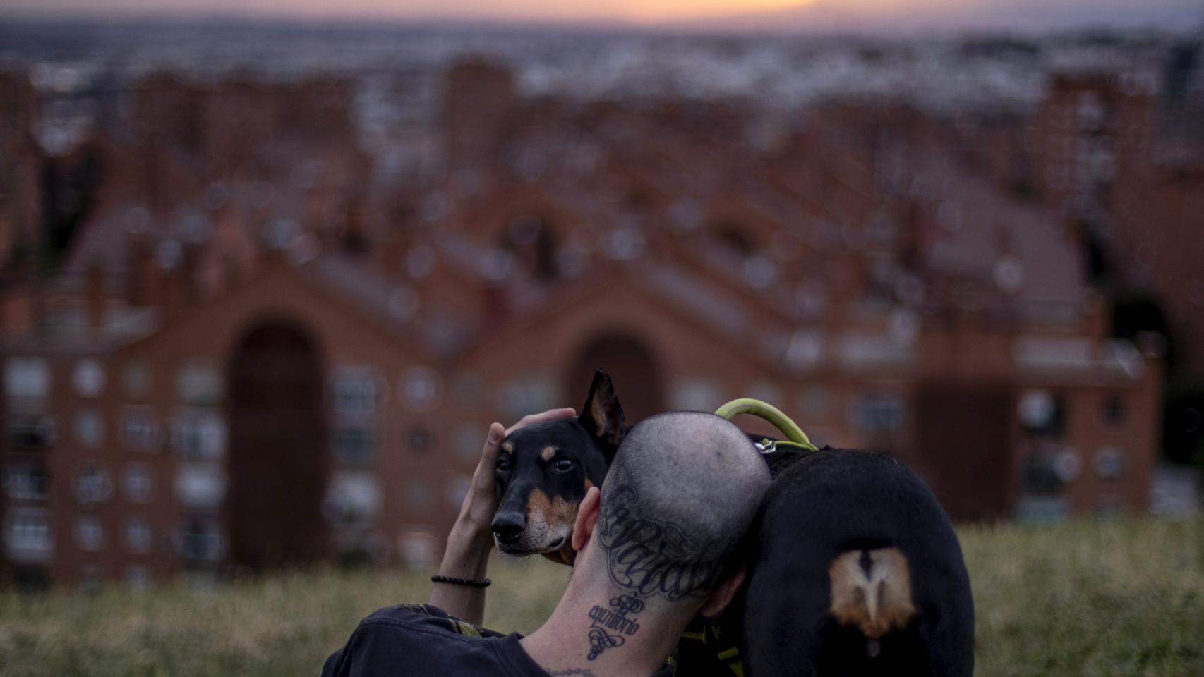 Un hombre contempla el atardecer con su perro en el parque del cerro del tío Pío, en Madrid.
