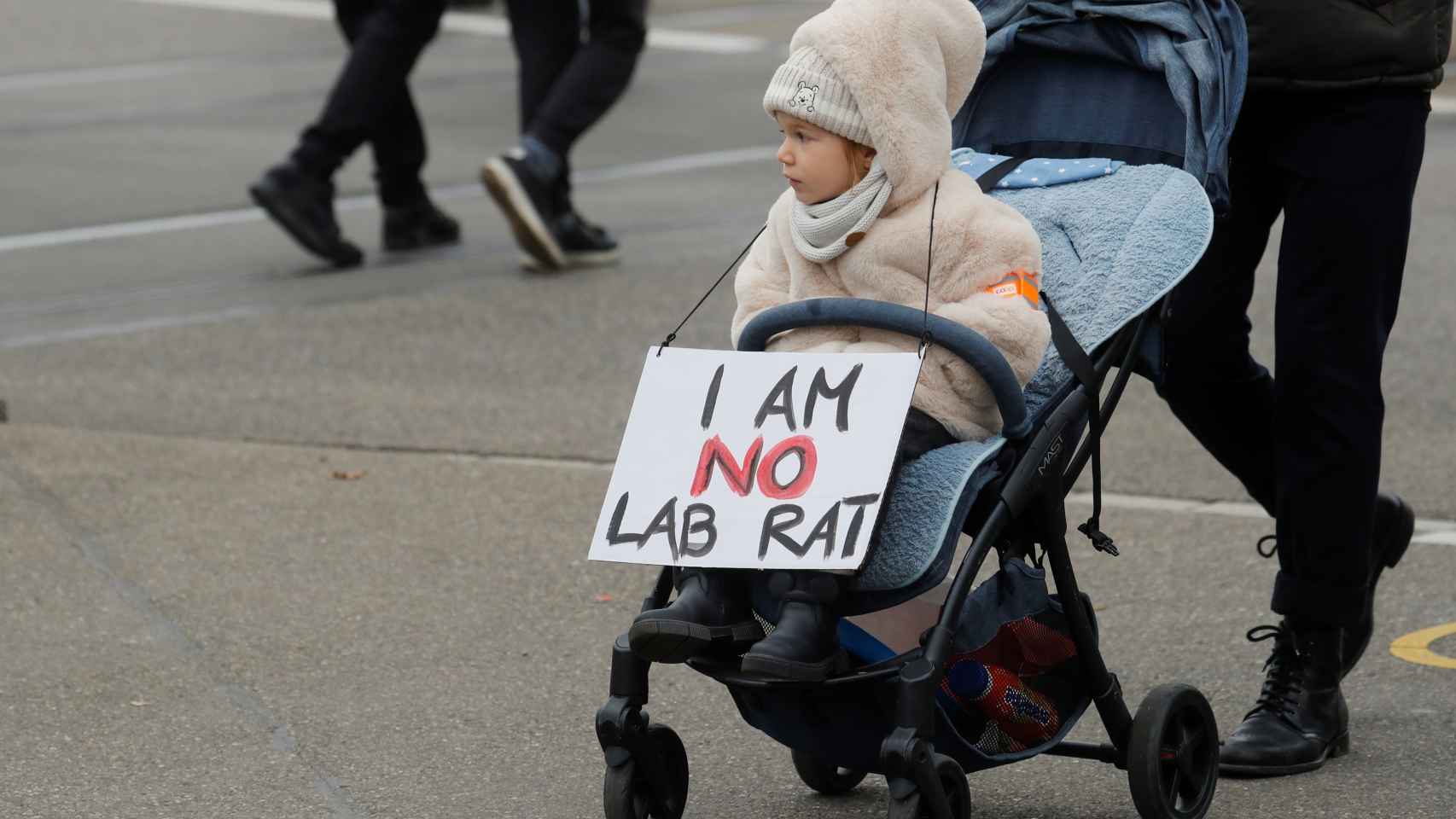 Una niña acompaña a su familia en una manifestación con un cartel: No soy una rata de laboratorio, haciendo referencia a la obligatoriedad de la vacuna en Austria.