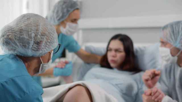 Una mujer da a luz en un hospital asistida por médicos y enfermeras.