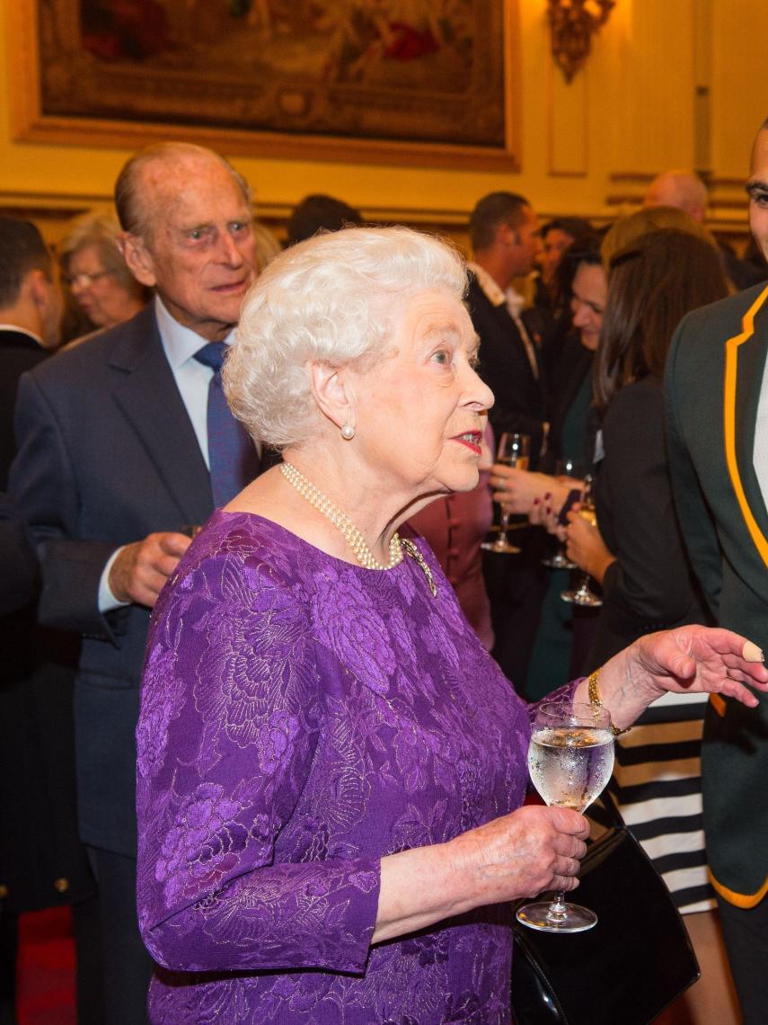 La reina Isabel II con una copa en la mano.