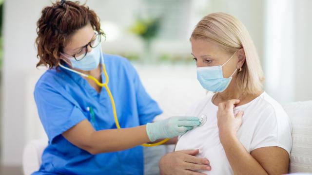 Una enfermera trata a una mujer con mascarilla.