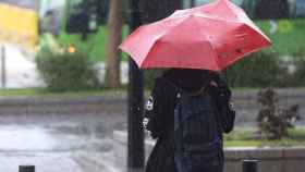 Un joven se protege de la intensa lluvia con un paraguas