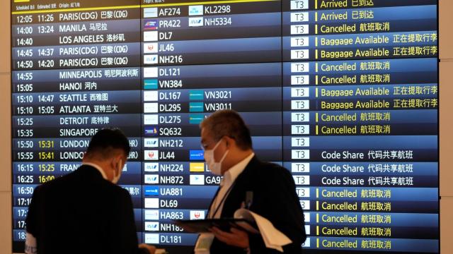 Pasajeros ante un panel de información en el aeropuerto internacional de Haneda, Tokio.