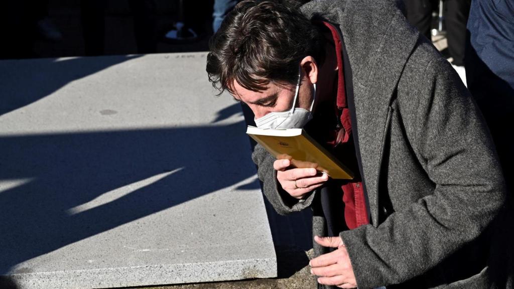 Luis García Montero dejando un ejemplar de 'Completamente viernes' sobre el féretro de Almudena Grandes.