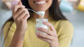 Una mujer comiendo un yogur desnatado.