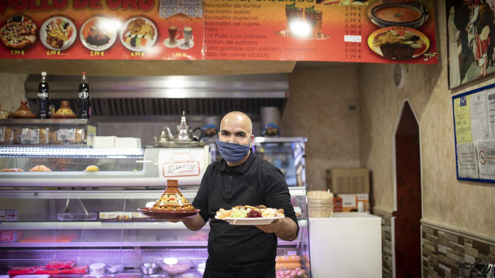 Elamin Elkaijairi, dueño de El Pollo de Oro, sostiene en sus manos los platos que ha servido a este medio.