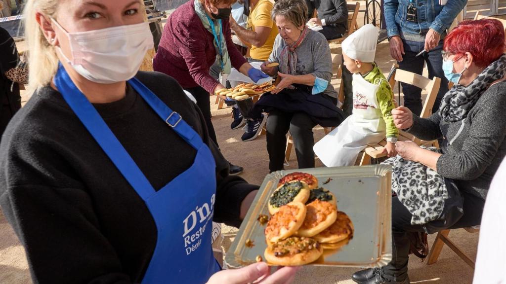 Una mujer reparte las típicas Cocas de la Marina durante el Festival Gastronómico de Dénia.