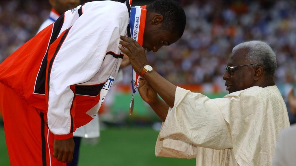 Lamine Diack poniéndole una medalla al deportista Kim Collins