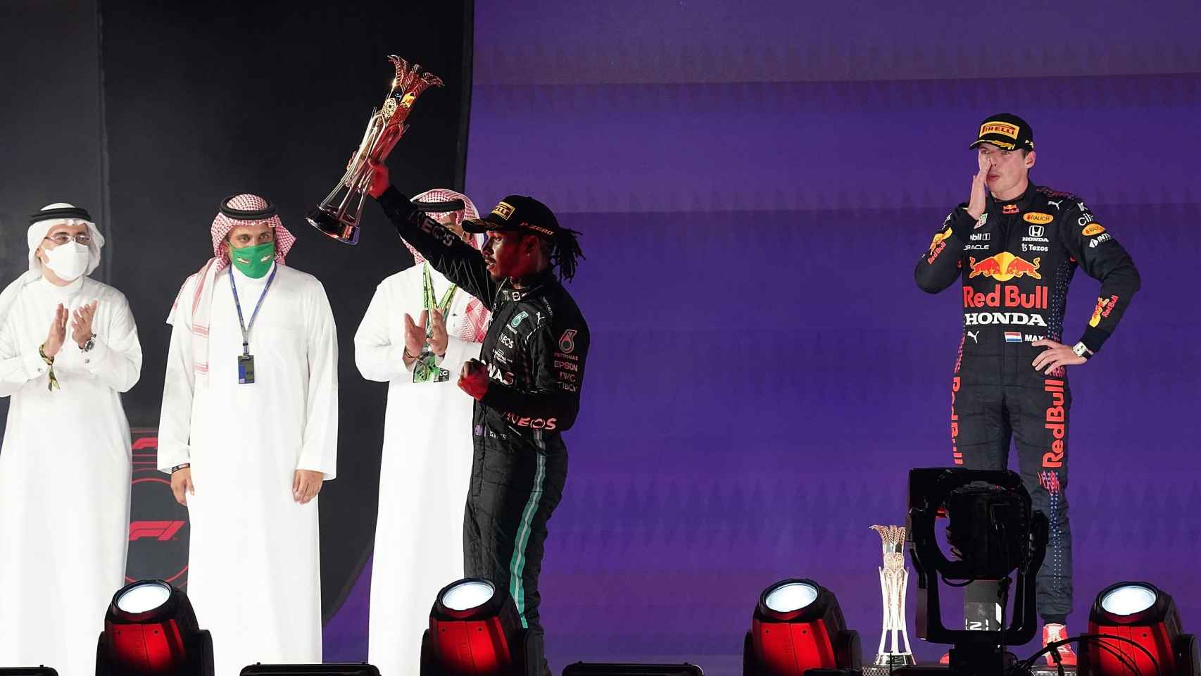 Verstappen mira a Hamilton como levanta su trofeo de ganador en Arabia Saudí
