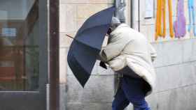 Un ciudadano con su paraguas de las fuertes rachas de viento