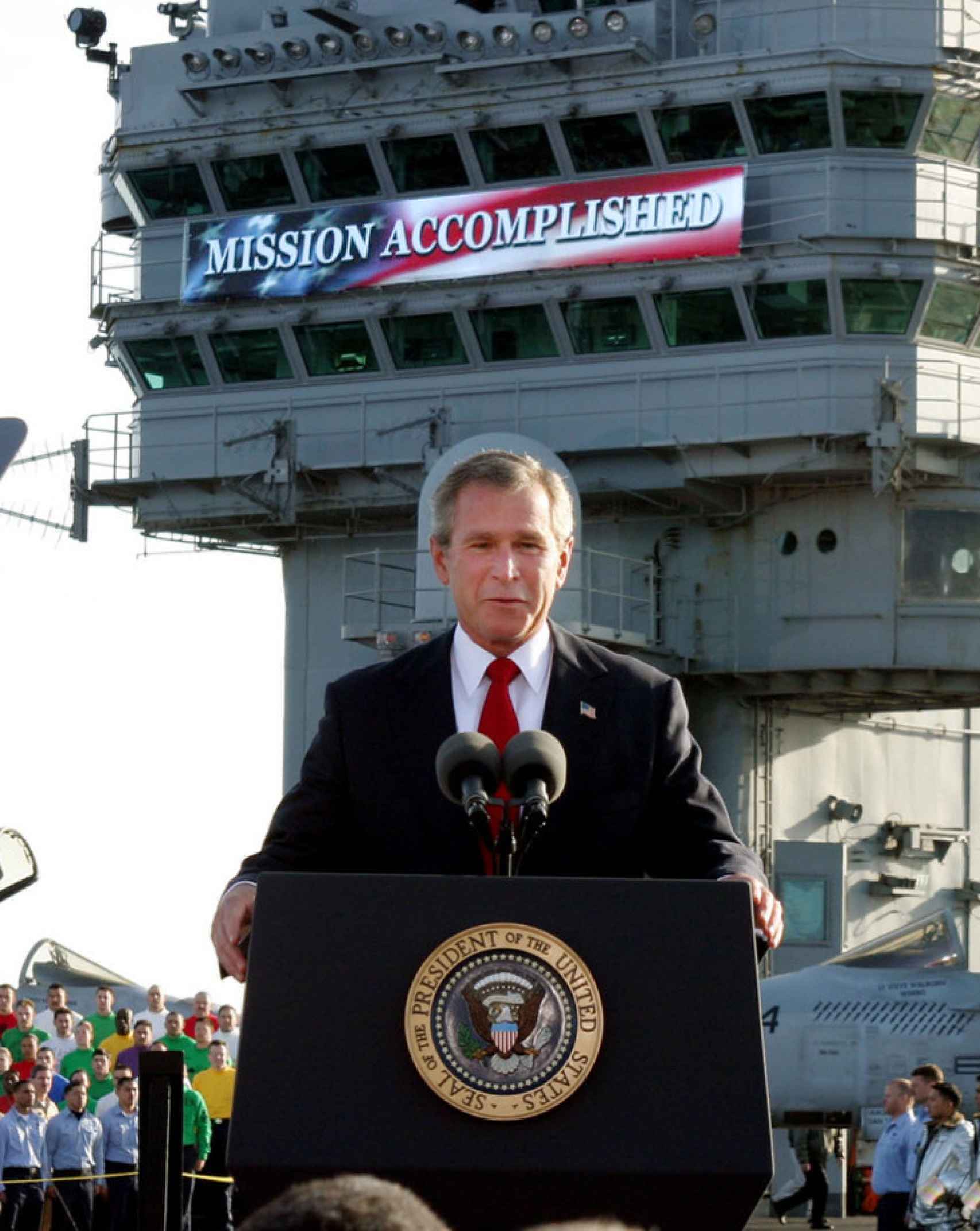 George W. Bush, en el portaaviones USS Abraham Lincoln, anuncia el triunfo de la coalición internacional en la guerra de Irak. Tras él aparece un letrero con las palabras Mission accomplished (Misión cumplida).