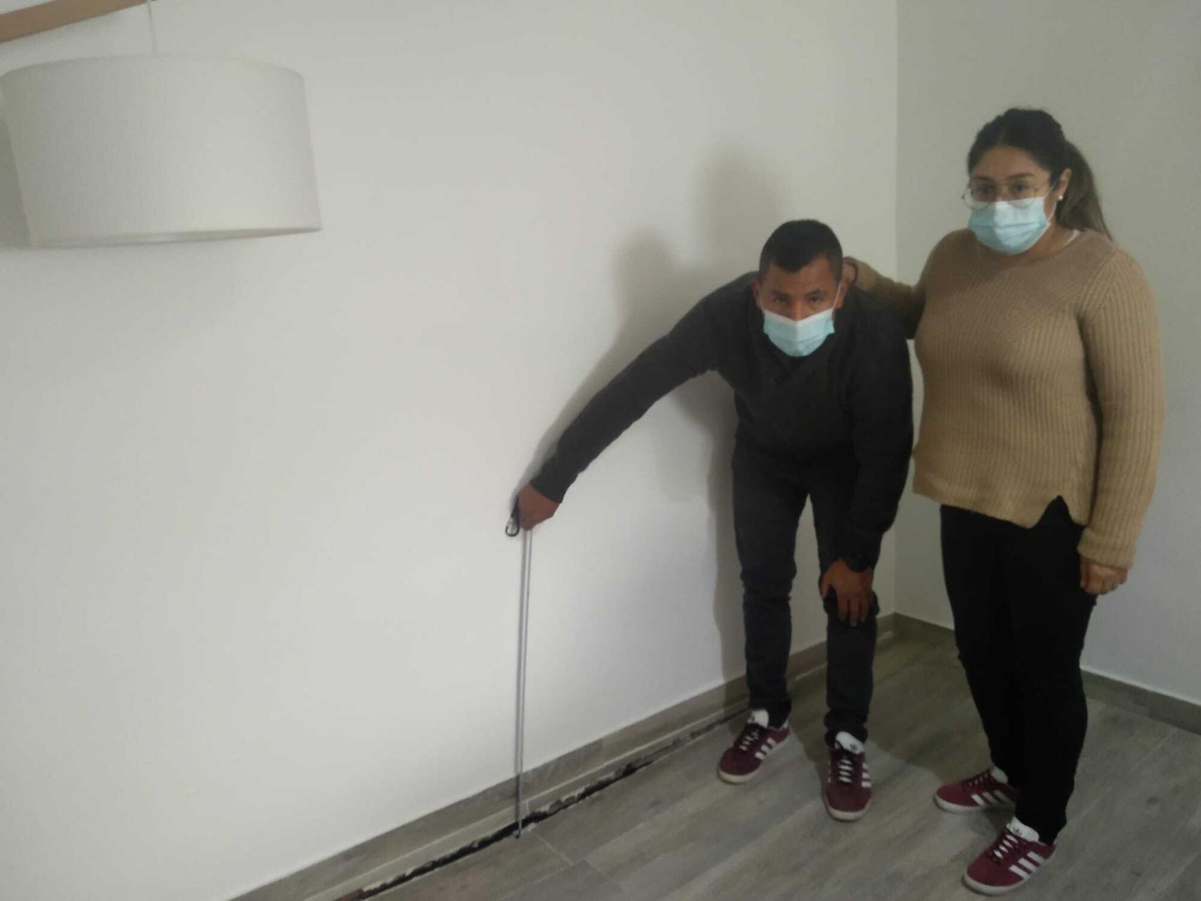 David y María, este lunes, con un metro, midiendo la anchura que tiene la brecha que atraviesa el salón de su casa.