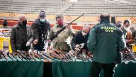 Varias personas examinan escopetas en la última subasta de armas de la Guardia Civil
