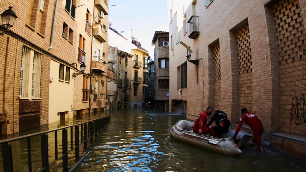 Trabajadores de Protección Civil de Tudela, subidos a una lancha en una calle inundada.