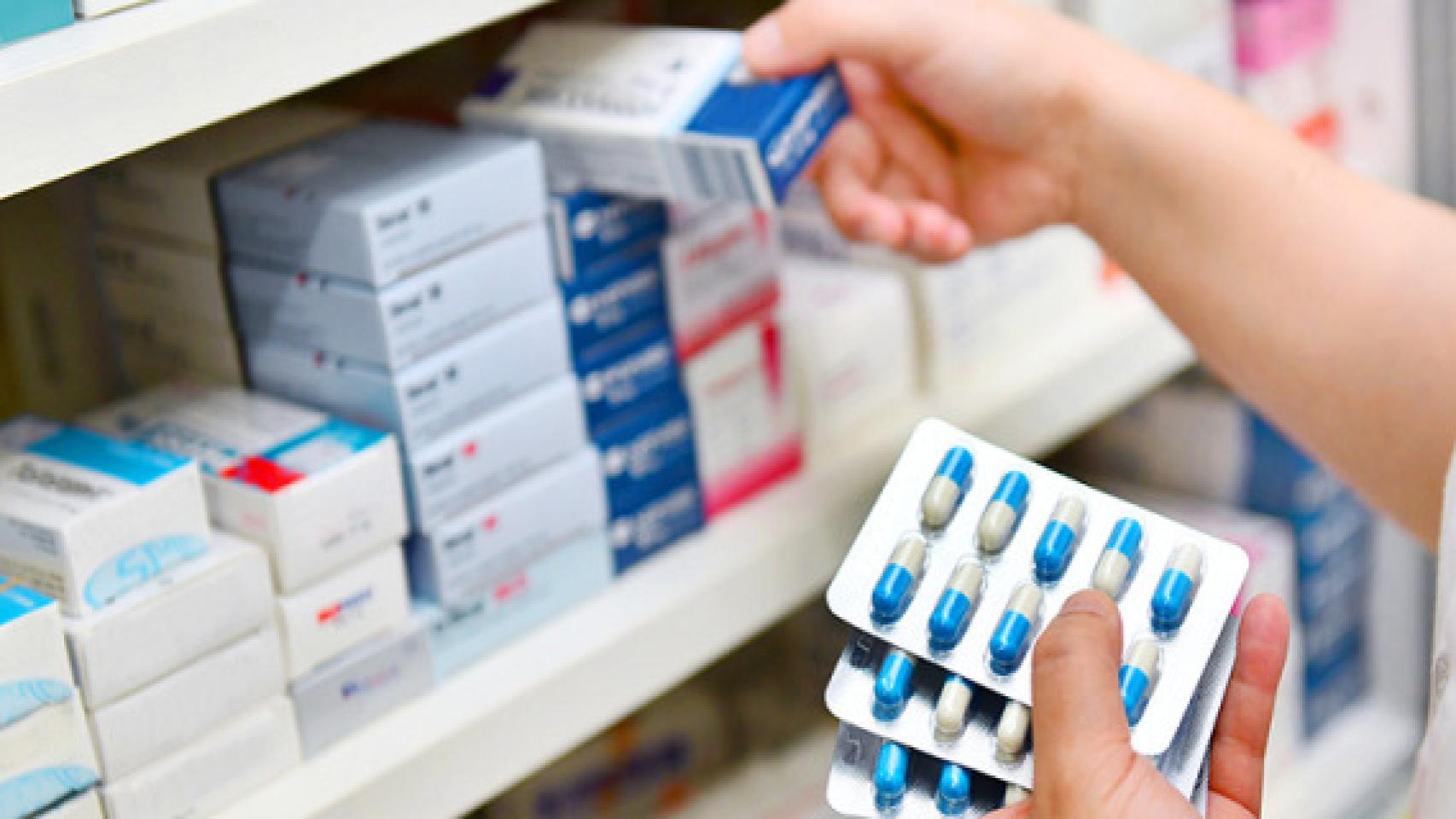 Un farmacéutico cogiendo medicamentos en una farmacia.