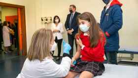 Una de las niñas que han sido vacunadas este miércoles en Toledo, siendo observada desde el fondo por la ministra.