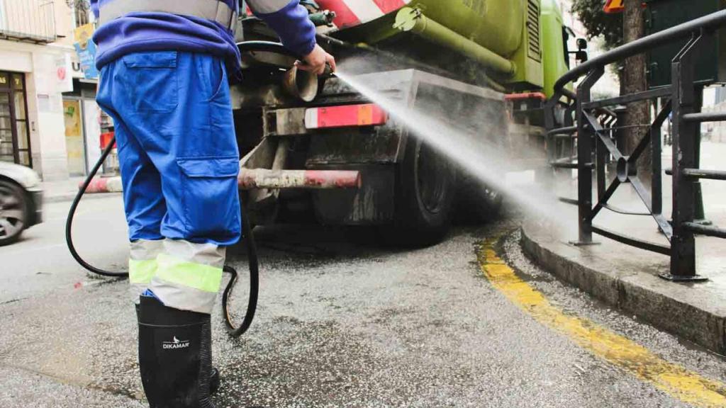 Labores de baldeo de uno de los operarios de Limasam, la empresa de limpieza de Málaga.