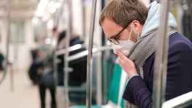 Una persona con mascarilla tose en el transporte público.
