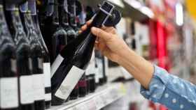 Un cliente alcanza una botella de vino en un supermercado.