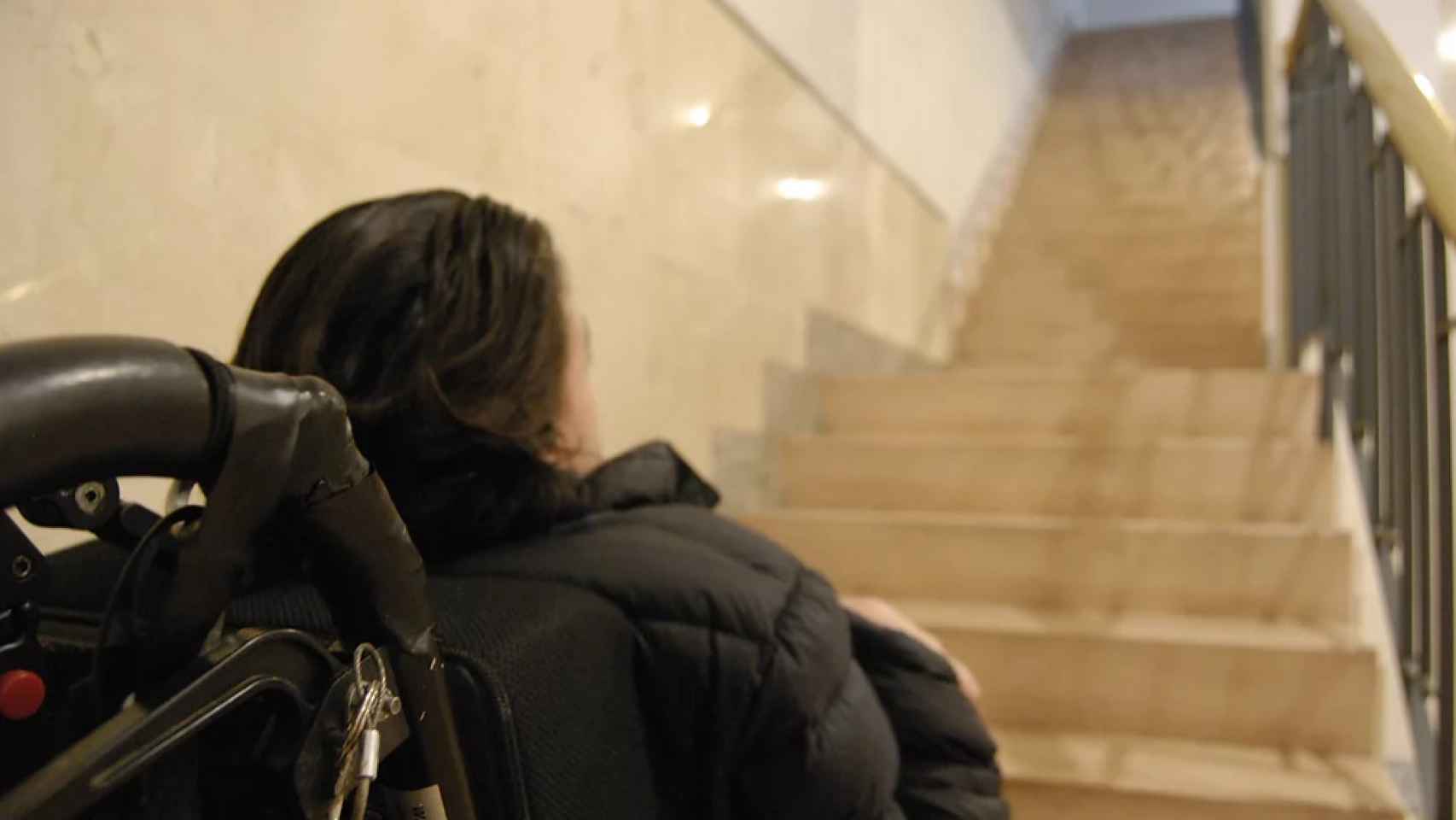 Una chica en silla de ruedas frente a unas escaleras