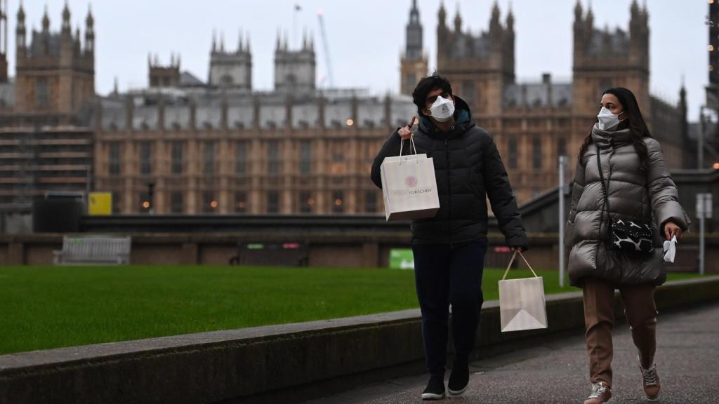 Dos ciudadanos pasean con compras navideñas cerca del Big Ben.