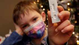 Un niño muestra un test de antígenos postivo. EFE/EPA Olivier Hoslet