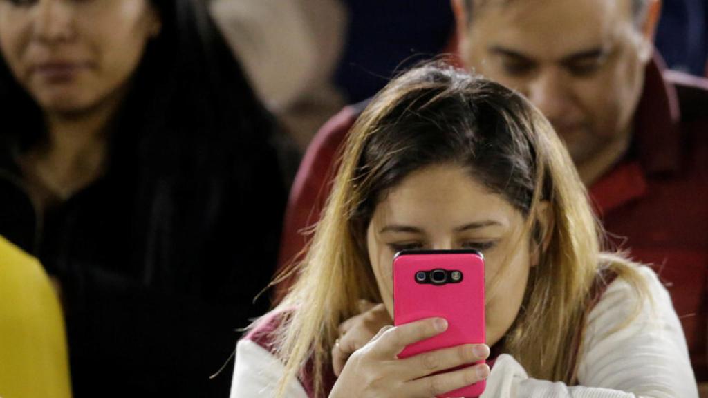 Una joven mirando su teléfono móvil.