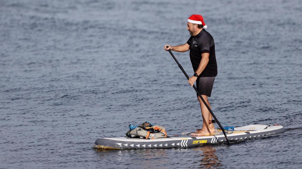 Una persona practicando surf con un gorro de Papá Noel en la Comunidad Valenciana.