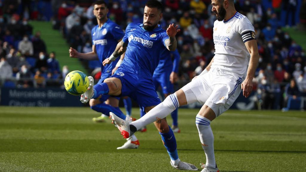 Karim Benzema golpeando con la puntera el balón ante la presión del Getafe