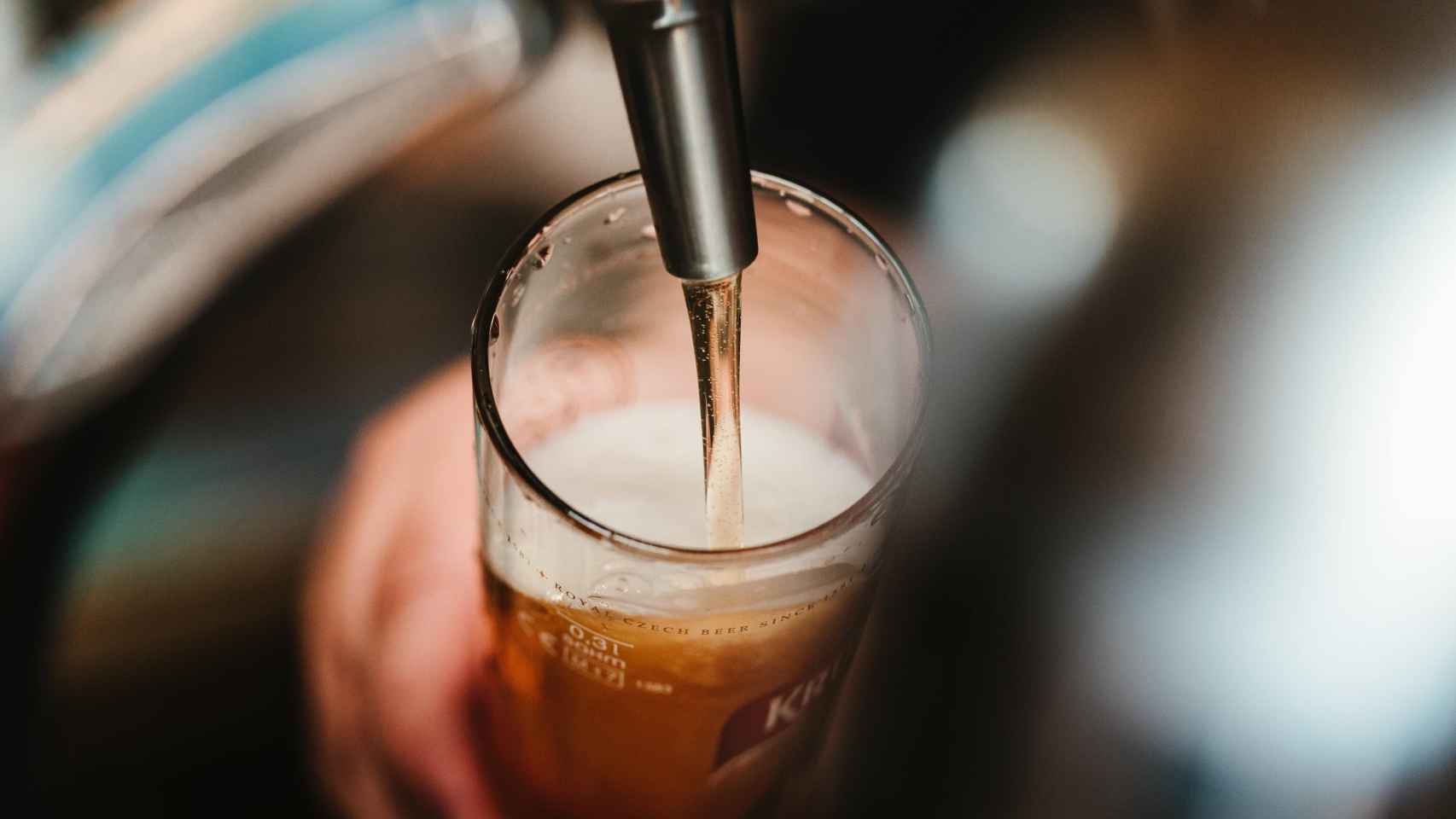 Un camarero sirve una cerveza en la barra de un bar.